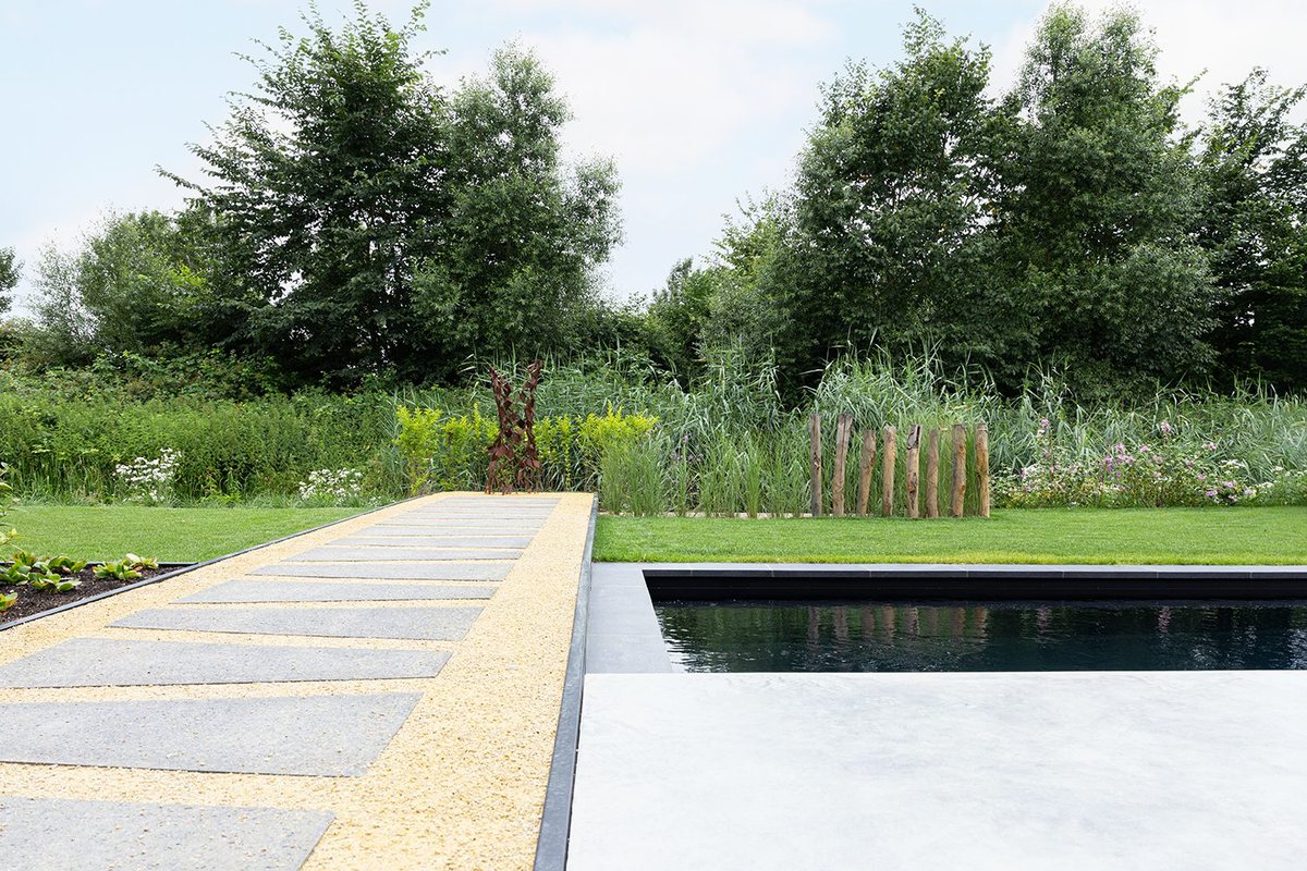 Zwembad met terras en natuurlijke beplanting langs de rand